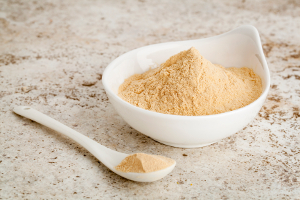 maca root powder - a small bowl with a spoon against ceramic tile surface